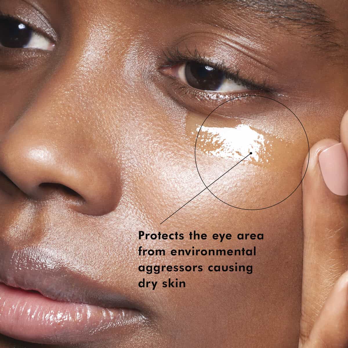 Close-up of a woman applying skincare cream to dry skin under her eye.