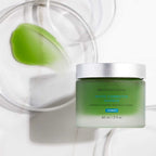 Green skincare masque in jar with botanical ingredients for calming skin.