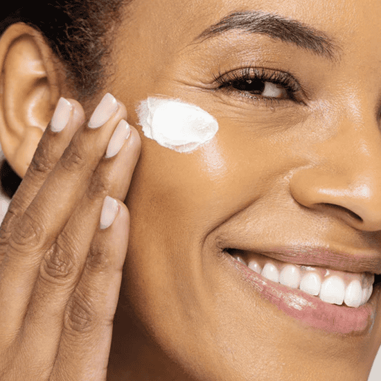 Woman applying skincare cream on her face for healthy, glowing skin.
